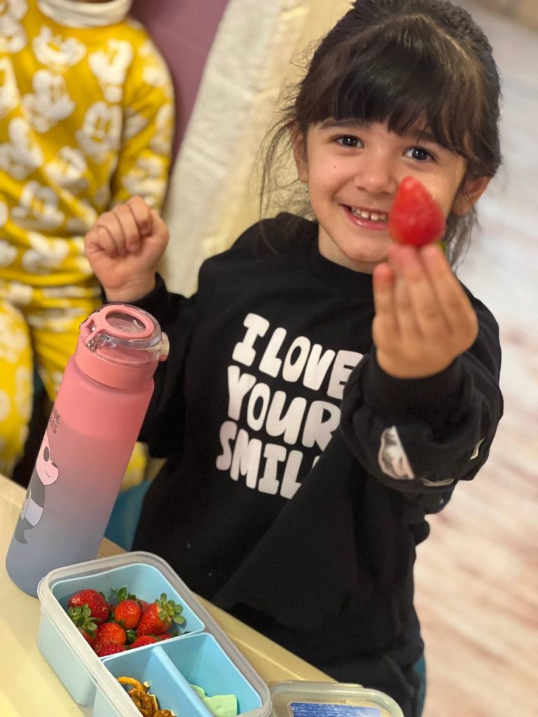 کودک شاد که یک توت فرنگی در دستش دارد